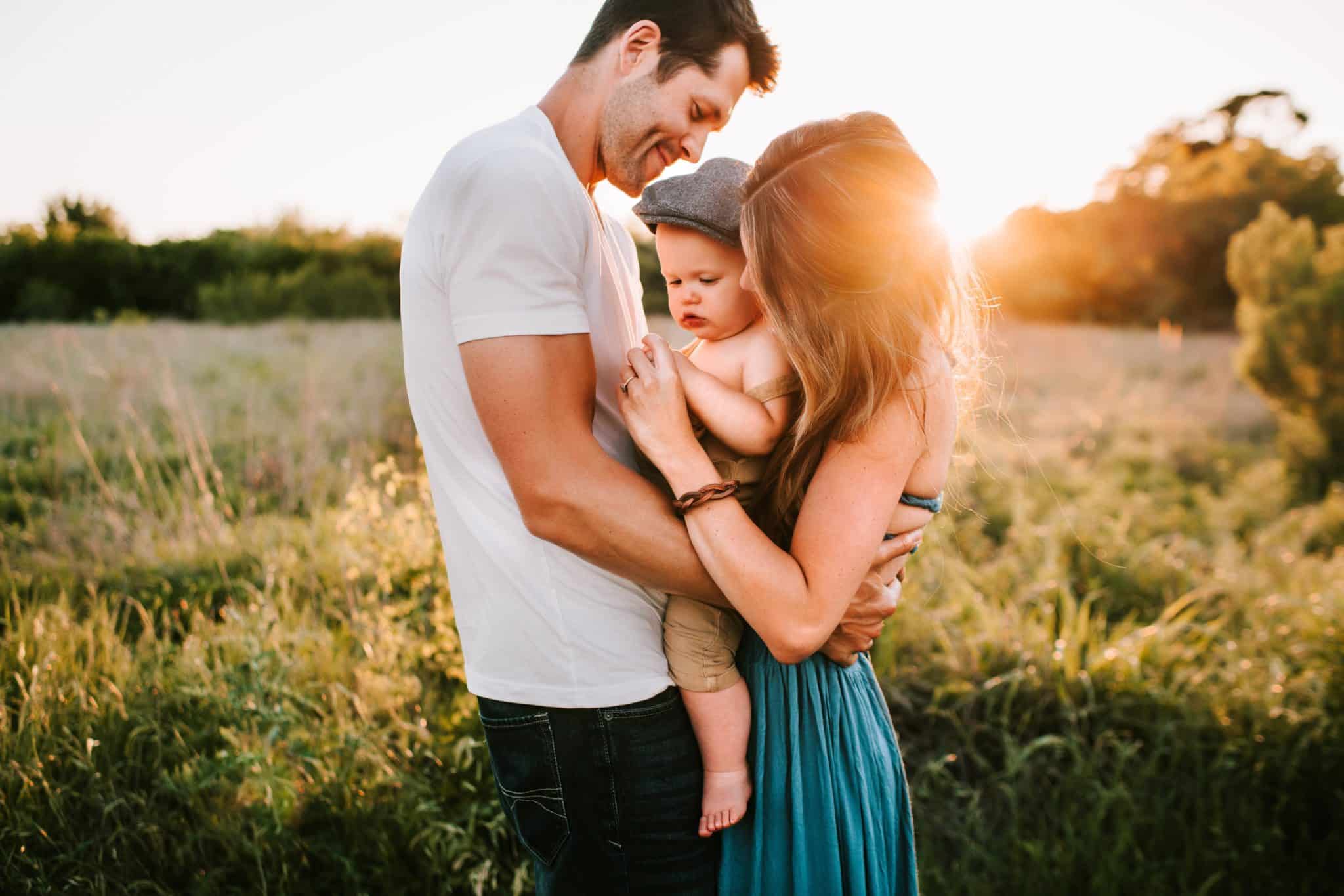 Husband and Wife standing outdoors holding their baby for Life Insurance.